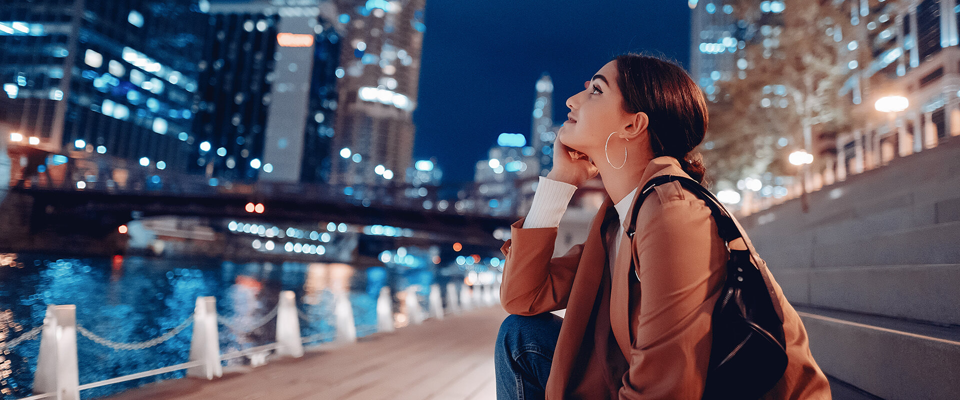 Woman sitting by Chicago river at night